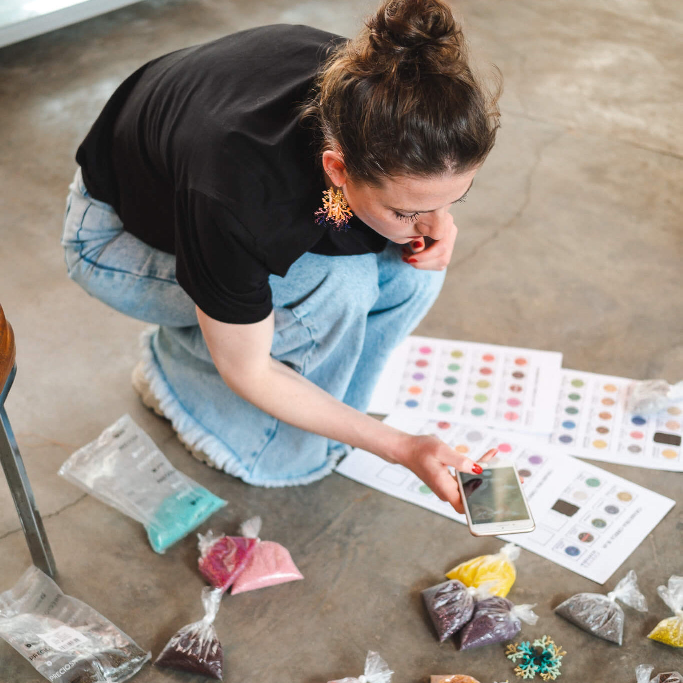 Lara van TOAIE stelt kleurencombinaties samen met gekleurde kralen op de vloer van het atelier in Colombia