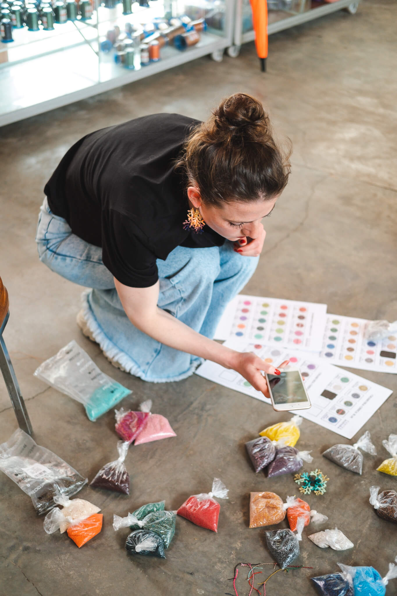 Lara van TOAIE stelt kleurencombinaties samen met gekleurde kralen op de vloer van het atelier in Colombia