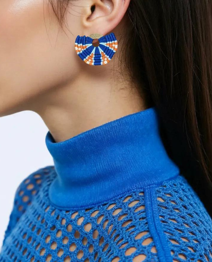 Vrouw draagt The Vagabond, handgemaakte geknoopte statement oorbellen in blauw en oranje, gemaakt in Colombia